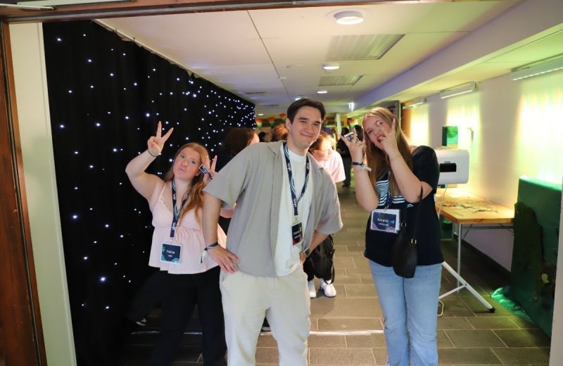 Tre unga personer poserar i en korridor med festivalpass