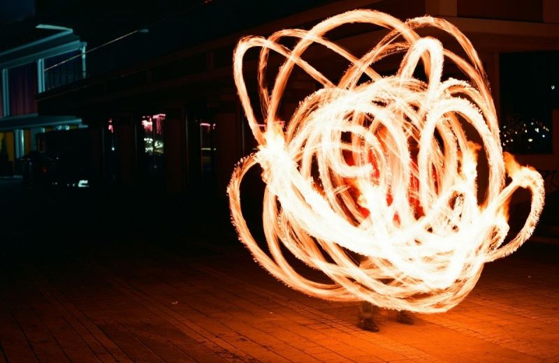 Virvlande eldspår bildar ljuscirklar runt en person på en mörk gård