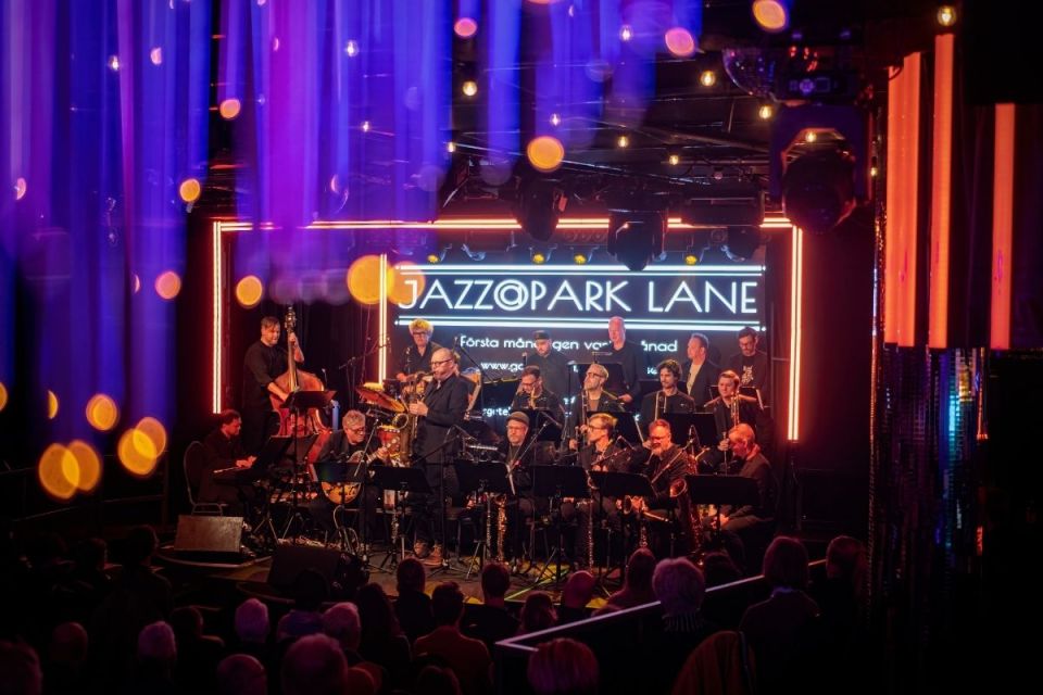 Bild på ett band på scen, med texten "Jazzopark Lane" som bakgrund