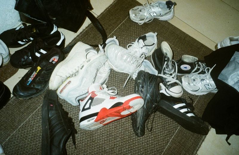 En salig blandning av olika sneakers ligger slängda på en dörrmatta.